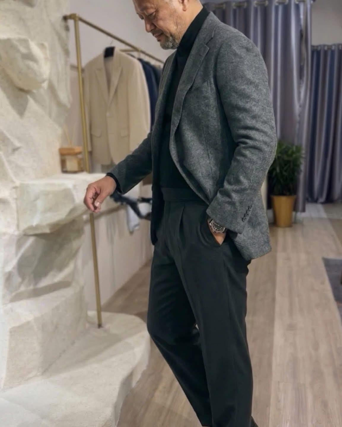 Client wearing a charcoal tailored suit in the showroom | Khách hàng mặc suit xám than may đo tại showroom