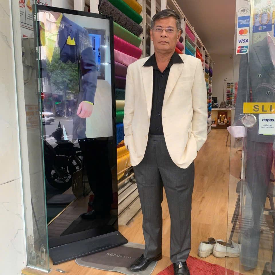 Client wearing a white dinner jacket at the showroom entrance | Khách hàng mặc áo khoác dự tiệc trắng tại lối vào showroom
