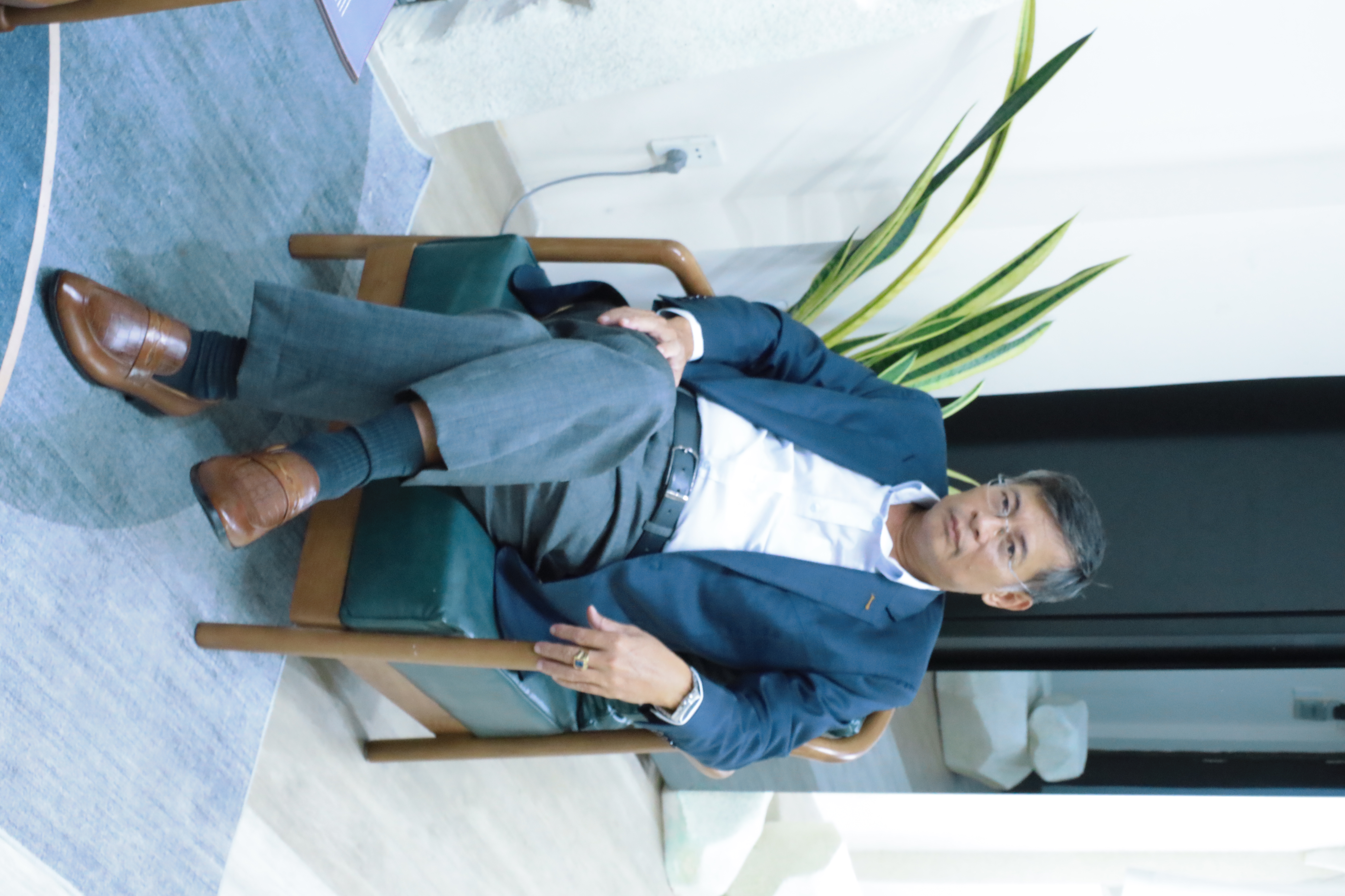 Client in a blue suit seated in the showroom | Khách hàng mặc suit xanh ngồi tại showroom