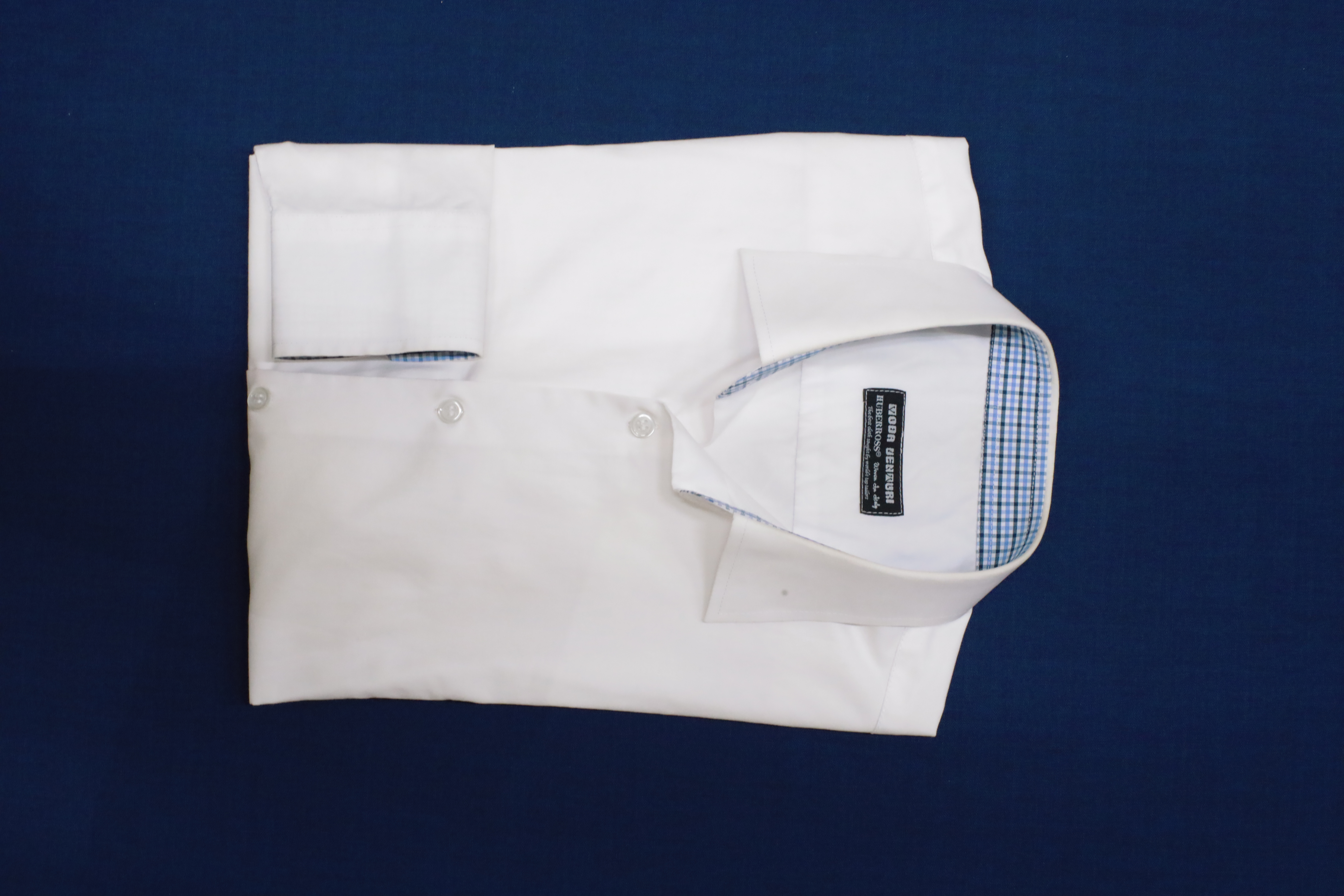 White tailored shirt folded on navy cloth | Sơ mi trắng may đo gấp trên nền vải navy